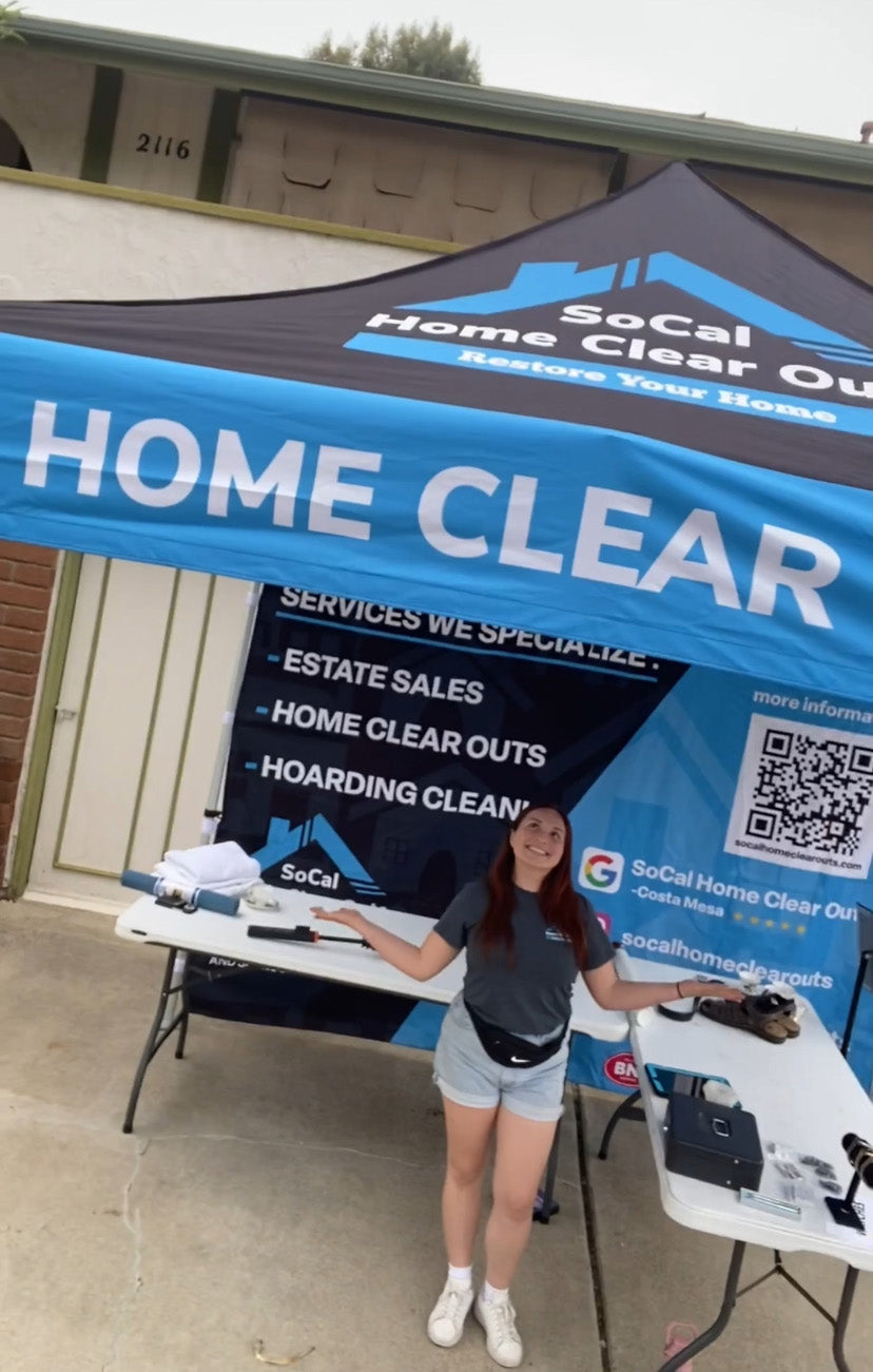 Person standing under a 'SoCal Home Clear Out' tent with promotional materials.
